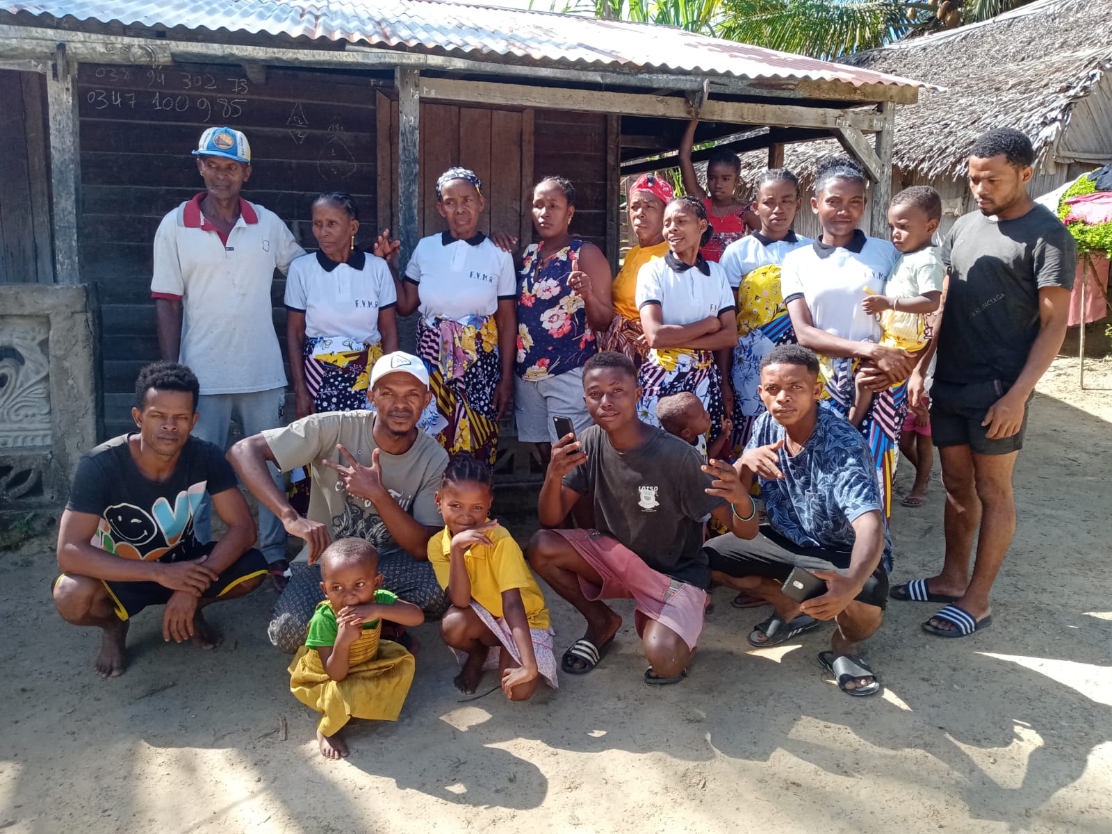 Larger group of farmers — women, men and children gathered in front of the farm building